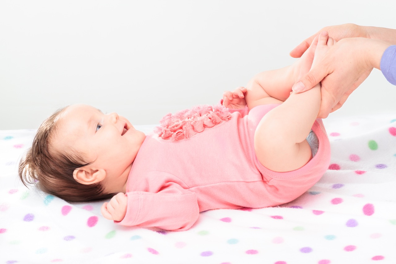 Mom holding her little daughter's feet neonata fisioterapista